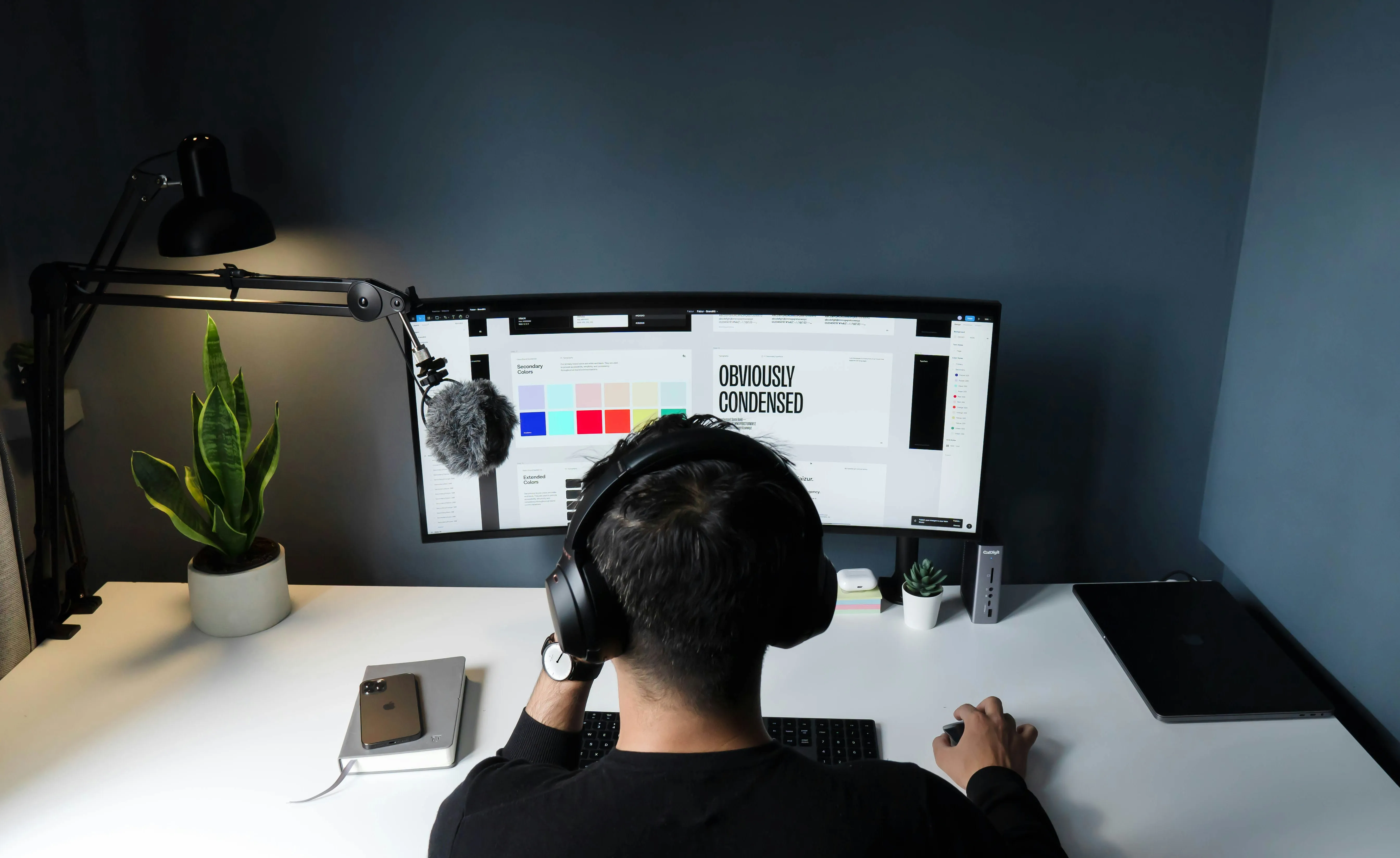 Graphic designer working at a modern desk setup with a curved monitor